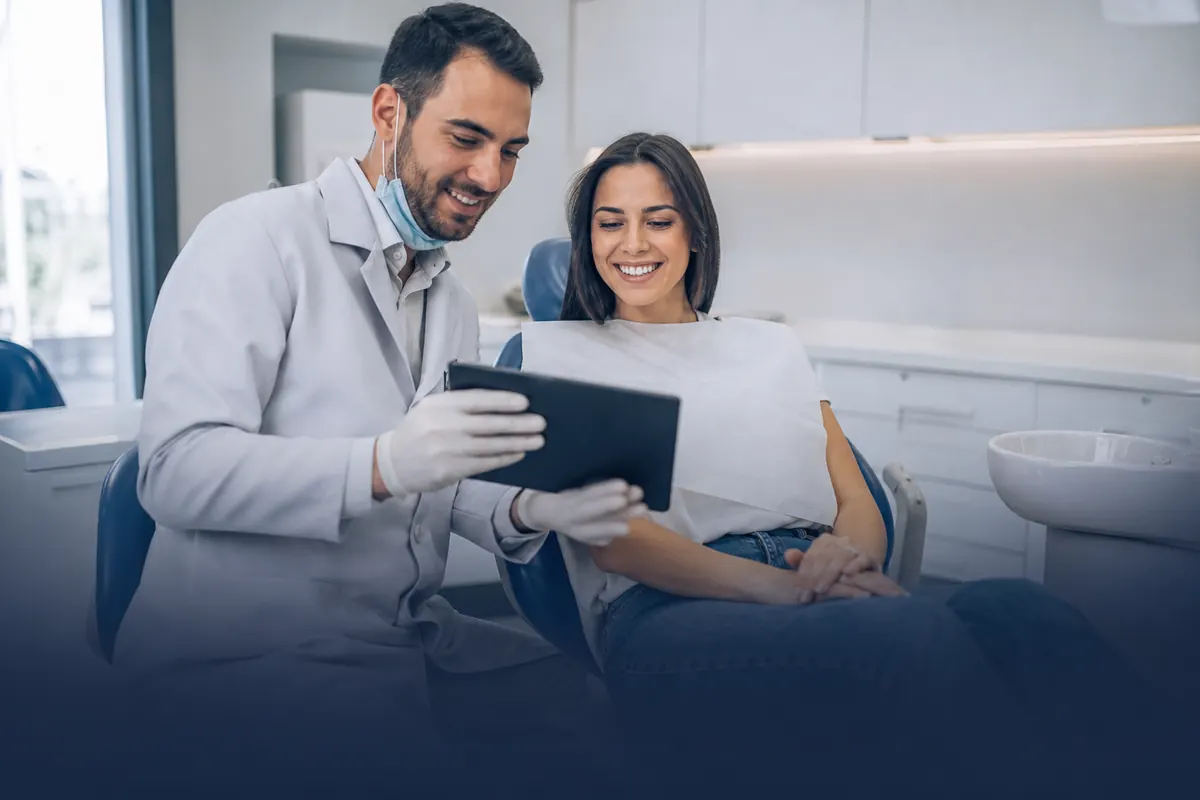 Dentista mostrando o tratamento a uma paciente no tablet